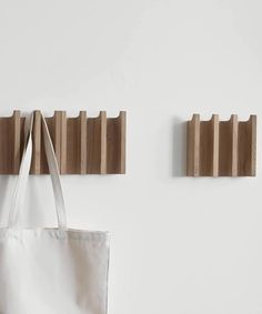 two wooden pegs hang on the wall next to a white bag