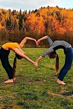 two women doing handstands in a field with trees in the backgroud