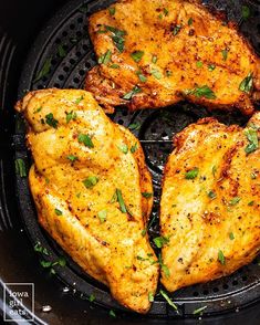 four pieces of chicken cooking in an air fryer with herbs on the top and bottom