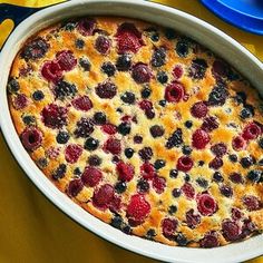 a blueberry and raspberry cake in a white dish on a yellow tablecloth