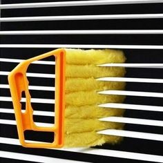 a yellow dust brush hanging on the side of a window