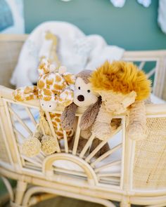 two stuffed animals sitting on top of a white chair next to a baby crib