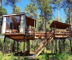 two cabins in the woods with stairs leading up to them and windows on each side