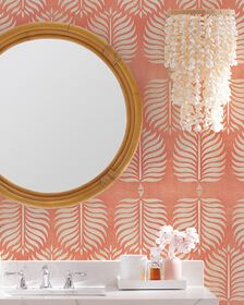 a bathroom with pink wallpaper and a round mirror