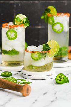 two glasses filled with ice and limeade sitting on top of a marble countertop