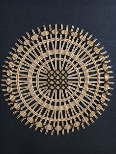 an intricately designed woven wall hanging on a blue background, with small holes in the center