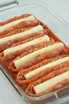 several sausages and cheese are in a glass casserole dish on the counter