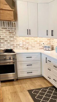 a kitchen with white cabinets and an area rug in front of the stove top oven