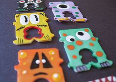 there are many different magnets that look like monster faces on the table, including one with eyes and mouth