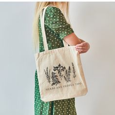 a woman carrying a tote bag that says herbs are people too