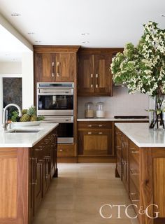 a kitchen with wooden cabinets and marble counter tops, along with an island in the middle