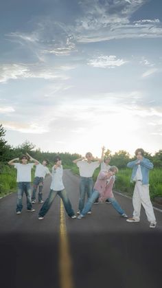 five young men standing on the side of a road with their arms in the air