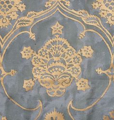 a blue and gold wallpaper with an intricate design on it's surface,