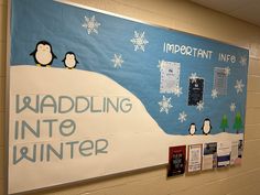 a bulletin board with penguins and snowflakes on the wall in front of it