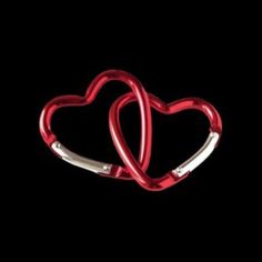 two red heart shaped metal clips against a black background