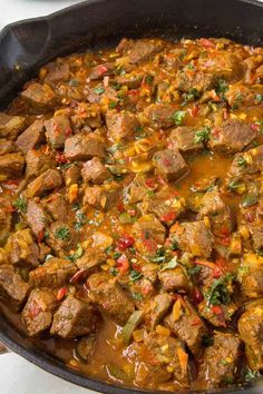 a pan filled with meat and vegetables on top of a stove