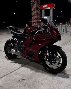 a red motorcycle parked in front of a gas pump