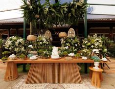 a wooden table topped with lots of white flowers and greenery on top of it