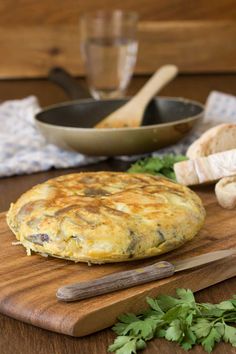 an omelet sitting on top of a wooden cutting board next to some parsley