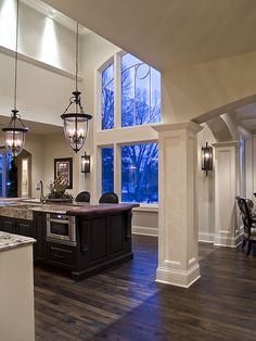 a large kitchen with an island in the middle and two hanging lights on each side