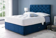 a bed with blue headboard and foot board in a room next to a window