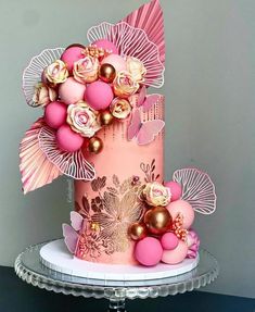 a pink and gold wedding cake with flowers on top