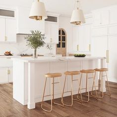 a kitchen with white cabinets and wooden flooring has three stools in front of the island