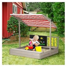 a child's play area in the yard with an umbrella over it and toys