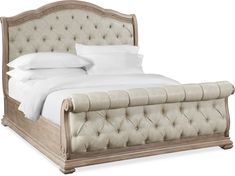 an upholstered bed with white sheets and pillows