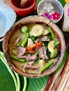 a bowl filled with meat and vegetables on top of a green leafy tablecloth