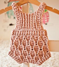 a crocheted bag hanging on a wooden hanger in front of a bed