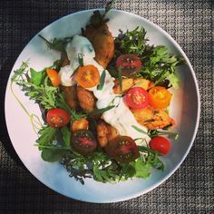 a white plate topped with lots of food on top of a wooden table next to a cloth