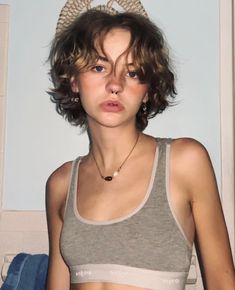 a woman with short hair wearing a gray tank top