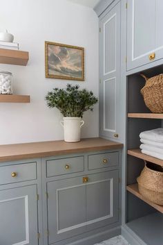 a bathroom with gray cabinets and white towels on the shelf next to it is a potted plant