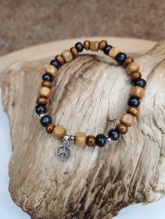 This bracelet is created with all varieties of wooden beads. It has different shades of browns with a peace sign charm hanging from it. It's earthy boho style ties together the beautiful simplicity of nature as well as the calming effects of peace. Both men and women can rock this accessory, as it is very neutral in it appearance! Wooden Beads Jewelry Greatergood, Cheap Bohemian Stretch Bracelet With Wooden Beads, Wooden Beads Jewelry, Wooden Bead Bracelet, Wooden Bead Jewelry, Wood Beads Jewelry, Bracelets Hippie, Wooden Beaded Bracelets, Hippie Accessories