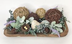 an arrangement of wicker balls and greenery on a wooden tray