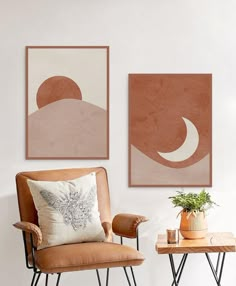 two paintings hang on the wall next to a chair and table with a potted plant