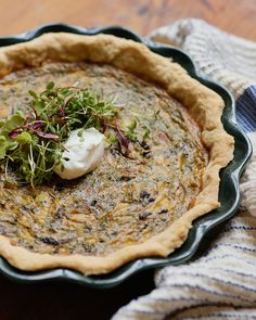 a quiche pie with sour cream on top and sprouts in the middle