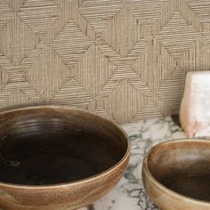 two brown bowls sitting on top of a marble counter next to a soap dispenser