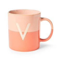 a pink and orange coffee mug with the letter v on it's side, in front of a white background