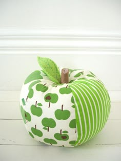 an apple with green apples on it is sitting on the floor in front of a white wall