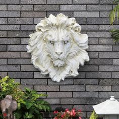 a white lion head mounted to the side of a brick wall next to potted plants