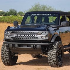 a black truck parked on top of a dirt field