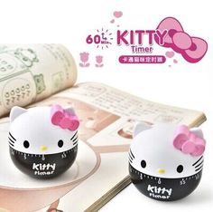 two hello kitty measuring cups sitting on top of an open book