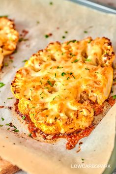 two pieces of bread with cheese and herbs on it sitting on a piece of parchment paper