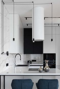 two blue chairs sit in front of an island with marble countertops and black cabinets