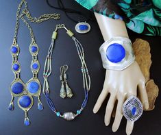 This LOT includes all 6 vintage Afghan jewelry pieces as shown. These pieces are mostly souvenir jewelry - that is jewelry that was made for sale in local souks for sale to travelers as simple trinkets. Not always exquisitely made, but replicas of old tribal jewelry pieces. The Lapis stones on several of them is lapis-composite - which is Lapis-Lazuli that has been pulverized, mixed with resin, and made into reconstituted stone. It is real lapis, just not in its natural state. Includes: ---> 1 Wide Afghan cuff bracelet with large Lapis stone (composite?) and incised band. 7-1/4 inch wrist circumference, including gap. ---> 1 Very-Large oval raised-dome ring with ornate design and lapis stone. Size 12.25 (Very large) ---> 1 Multi-strand Afghan necklace with lapis and adventurine beads. Larg Vintage Jewelry For Jewelry Making And Festivals, Vintage Decorative Jewelry For Festivals, Decorative Vintage Jewelry For Festivals, Antique Nickel-free Jewelry For Festivals, Artisan Handmade Jewelry Vintage Collection, Artisan Brass Jewelry For Collectors, Vintage Blue Jewelry With Unique Variations, Artisan Brass Jewelry Collectible, Bohemian Jewelry With Unique Variations For Collectors