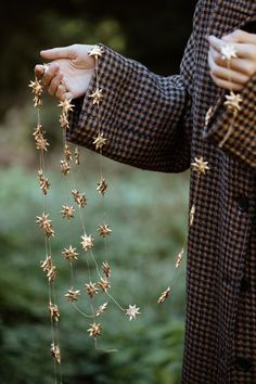 a person wearing a suit and holding some gold stars on their hand, with grass in the background