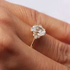 a woman's hand with a diamond ring on top of her finger and the other hand holding an engagement ring