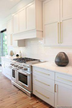 a kitchen with white cabinets and gold trim on the oven, counter tops and drawers